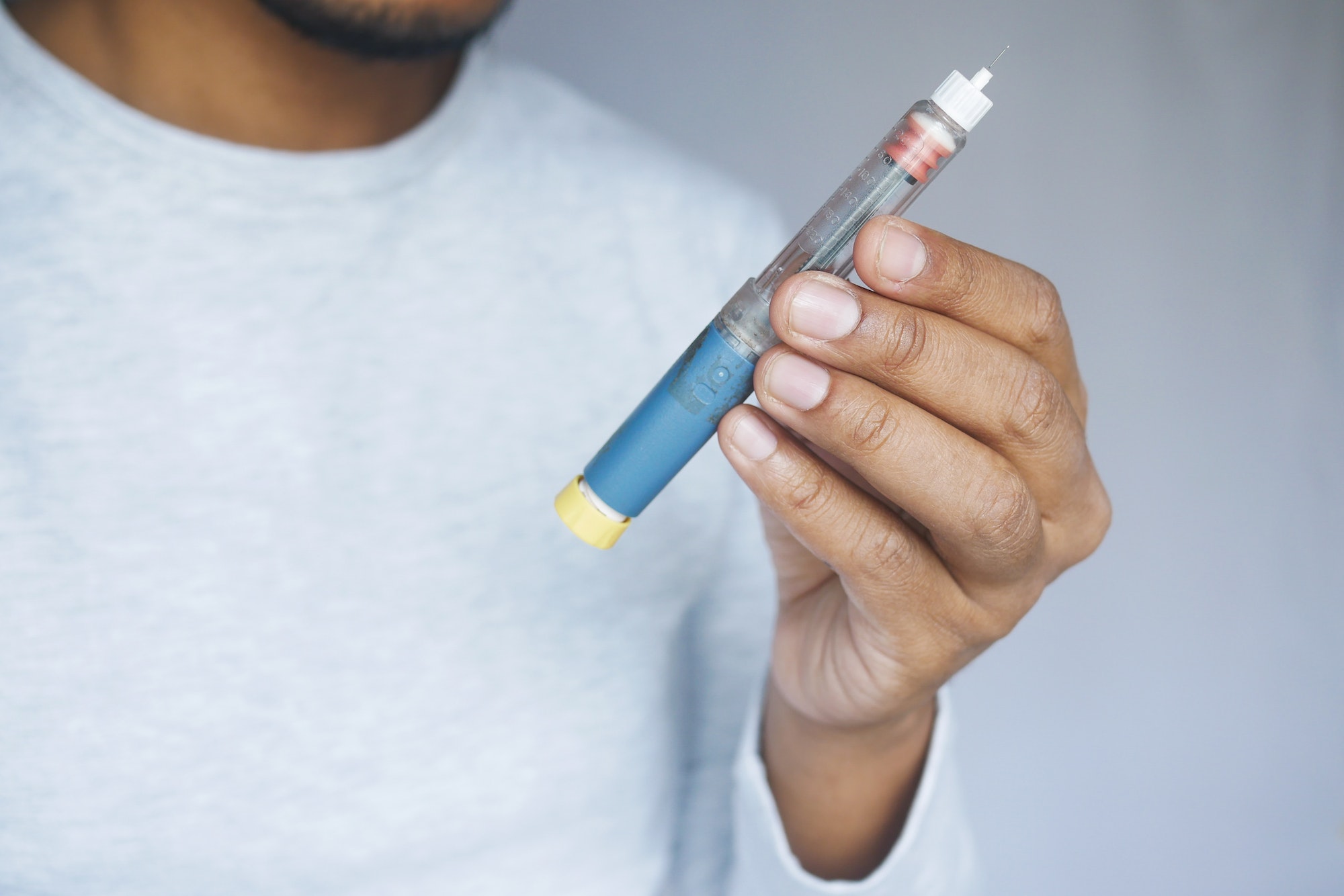 young man holding insulin pen close up